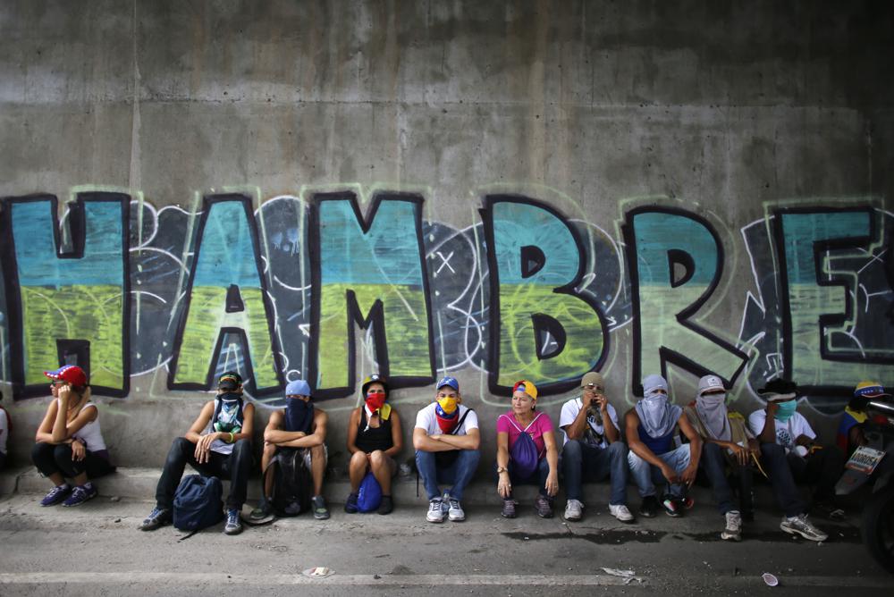 Manifestantes se sientan debajo de un puente que tiene un grafiti durante una protesta en Caracas, Venezuela, el 1/7/2017