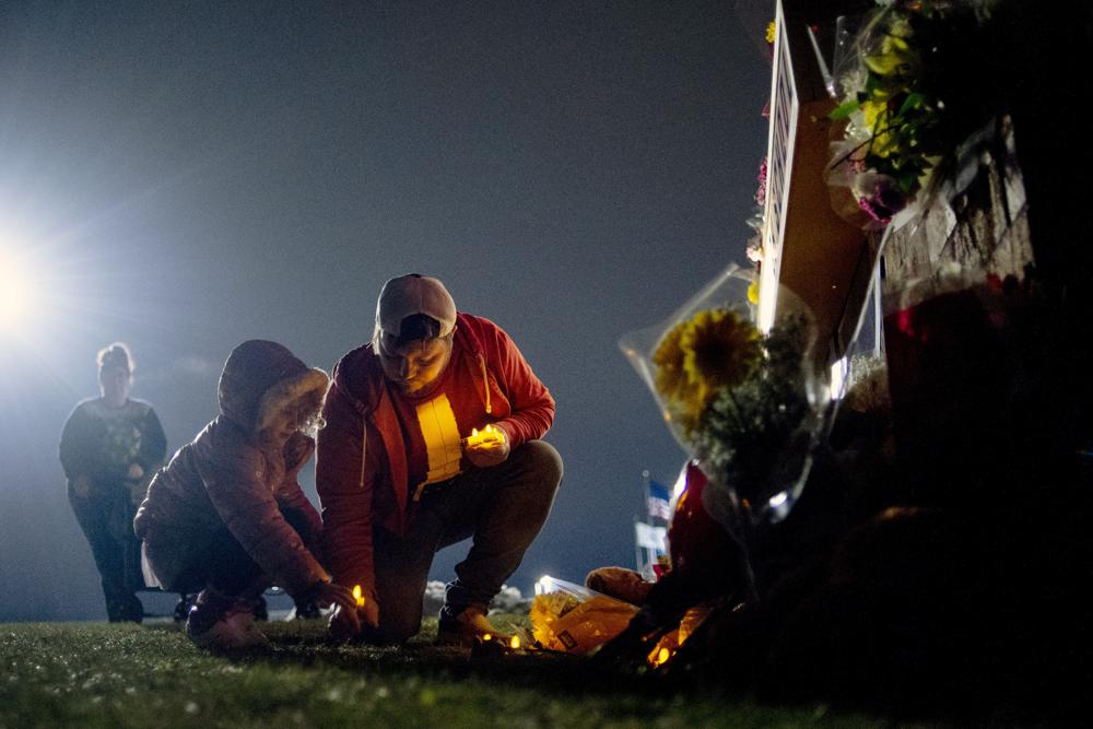 Coloca velas a la base de un memorial  de los muertos en tiroteo escolar el 30 de noviembre