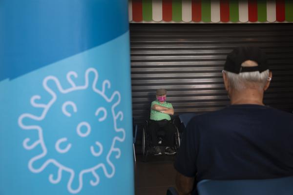 Hombres permanecen sentados después de recibir una tercera dosis de la vacuna de Pfizer-BioNTech contra COVID-19 en un centro de vacunación en Tel Aviv, Israel