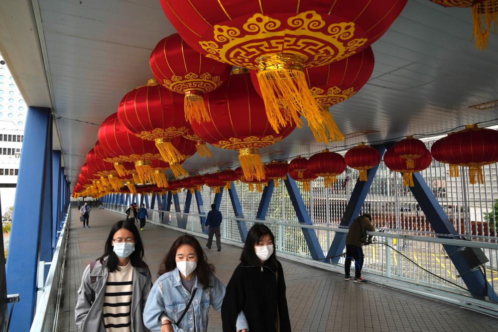 Gente con mascarillas pasa por un puente decorado por el Año Nuevo Lunar en Hong Kong