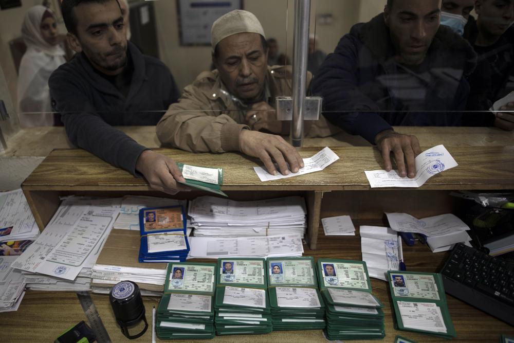 Tres personas recogen sus nuevos documentos nacionales de identidad en una oficina del gobierno en la Ciudad de Gaza el 5/1/2022
