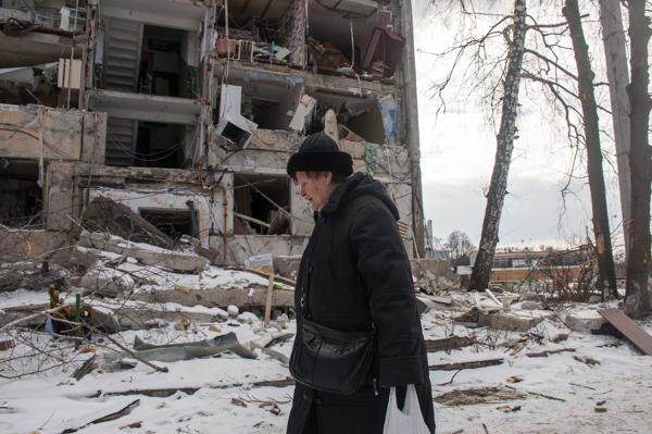 Mujer pasa frente a un edificio dañado por los bombardeos rusos, el domingo 13/3/2022, en Járkiv, Ucrania