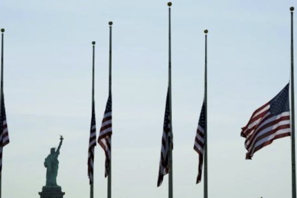 Vista desde Nueva York de banderas estadounidenses a media asta al otro lado de la bahía, en Jersey City, el 25 de mayo de 2022, en honor de las víctimas del tiroteo la víspera en una escuela primaria de Uvalde, Texas