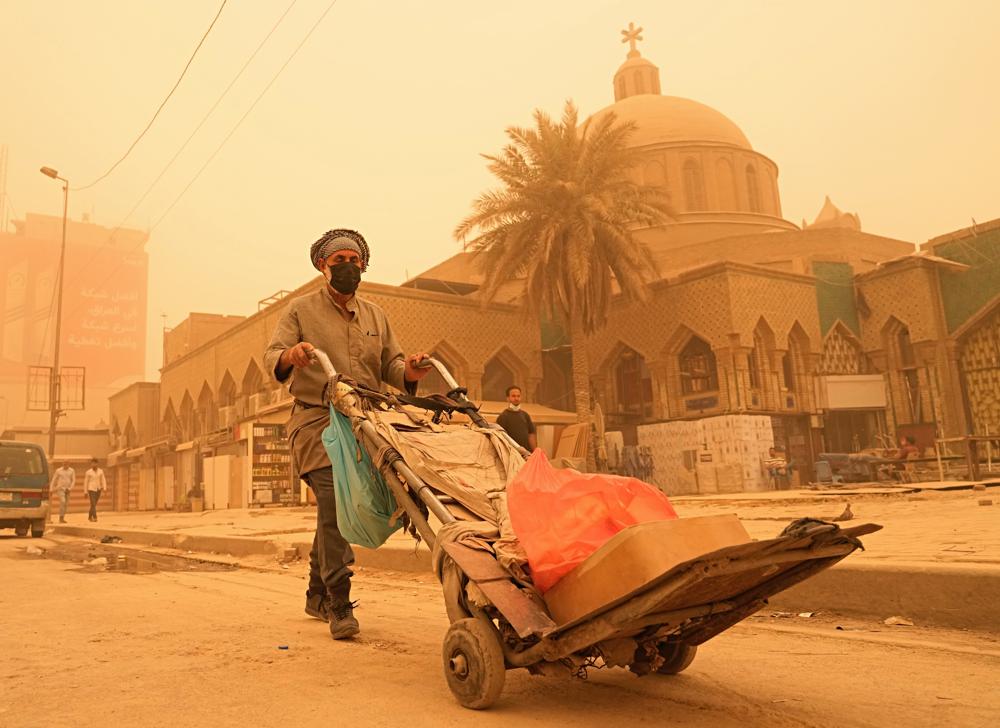 Un hombre empuja un carro el lunes 16/5/2022, durante una tormenta de arena en Bagdad, Irak