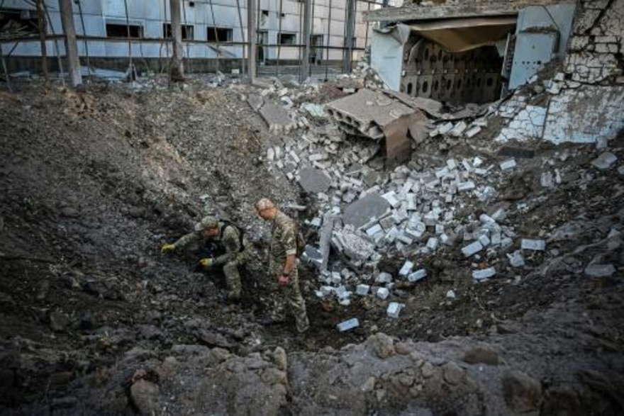 Dos soldados ucranianos examinan el cráter dejado por un ataque con misiles el 2 de septiembre de 2022 en el centro de Járkov, al este de Ucrania