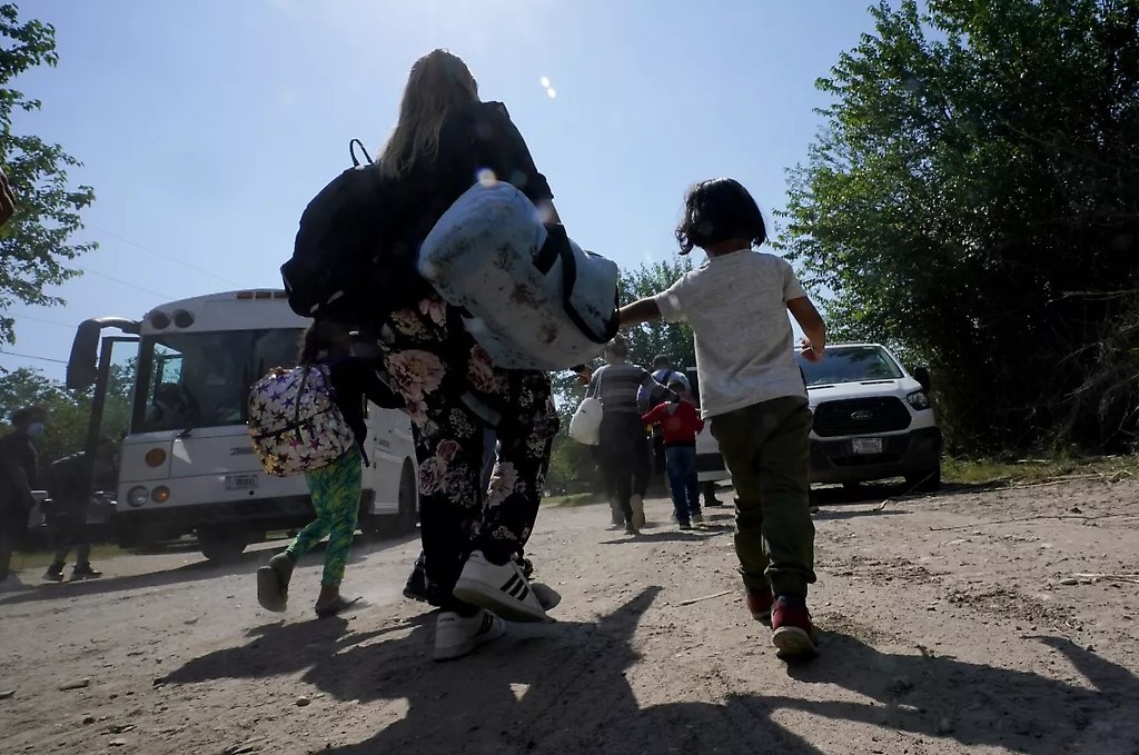 Una familia de migrantes venezolanos se dirige hacia un autobús de la Patrulla Fronteriza después de que cruzaran con otras personas de México hacia EEUU