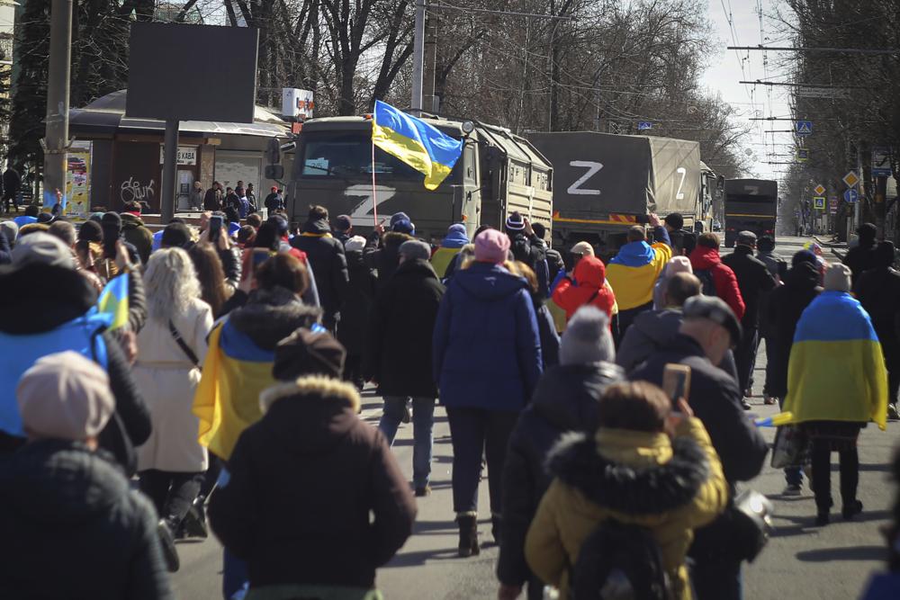 Personas con banderas ucranianas caminan hacia los camiones militares rusos durante una marcha contra la ocupación de Rusia, en Jersón, Ucrania