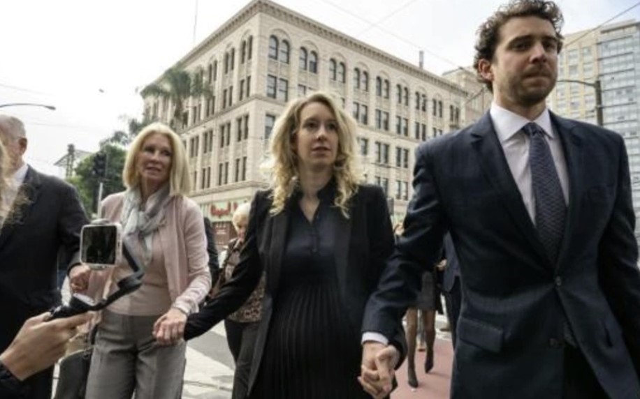La empresaria estadounidense Elizabeth Holmes (C) camina con su madre Noel Holmes y su socio Billy Evans hacia el tribunal federal para su audiencia de sentencia el 18 de noviembre de 2022 en San José, California