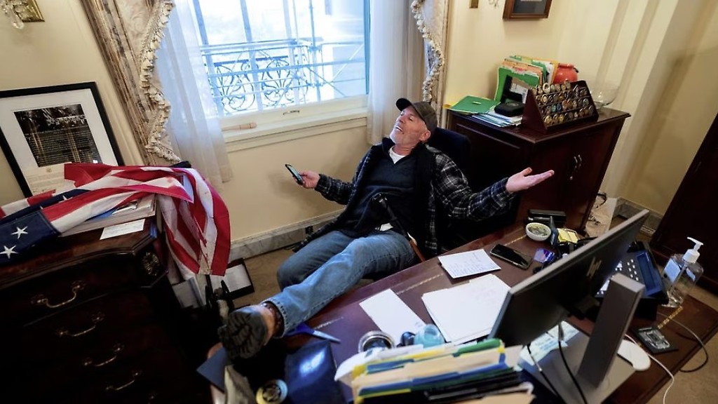 Richard "Bigo" Barnet, seguidor de Donald Trump, en el escritorio de la presidenta de la Cámara de Representantes, Nancy Pelosi, tras el asalto al Capitolio del 6 de enero de 2021 en Washington