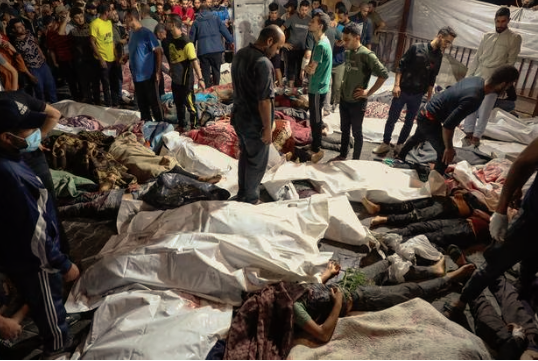 Personas reunidas alrededor de los cuerpos de palestinos muertos en un bombardeo de Israel contra el hospital árabe Ahli en el centro de Gaza.
