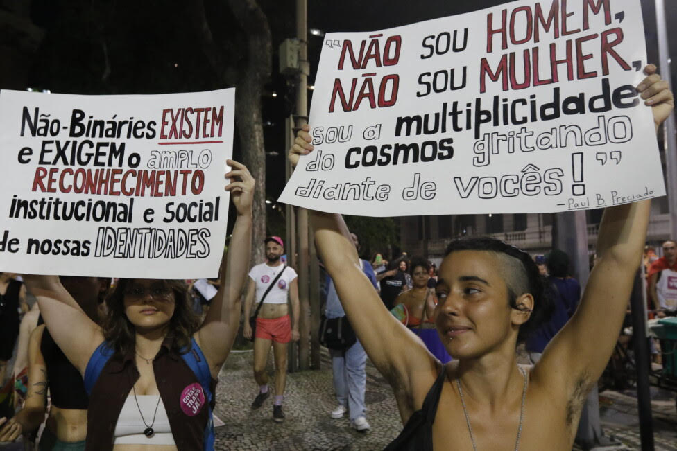 Dos activistas portan carteles reivindicativos en la Marcha Trans y Travesti