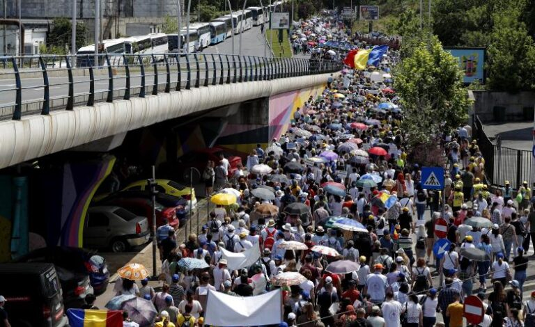 Docentes rumanos portan pancartas y ondean banderas sindicales durante una marcha de protesta sindical en Bucarest, Rumania