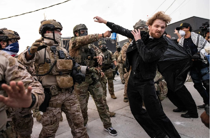 Un agente federal repele con gas al reverendo David Black, afuera de un centro del ICE en Chicago